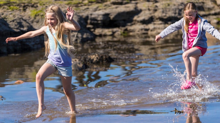 Girls paddling in a stream on the beach at Robin Hood's Bay, North Yorkshire